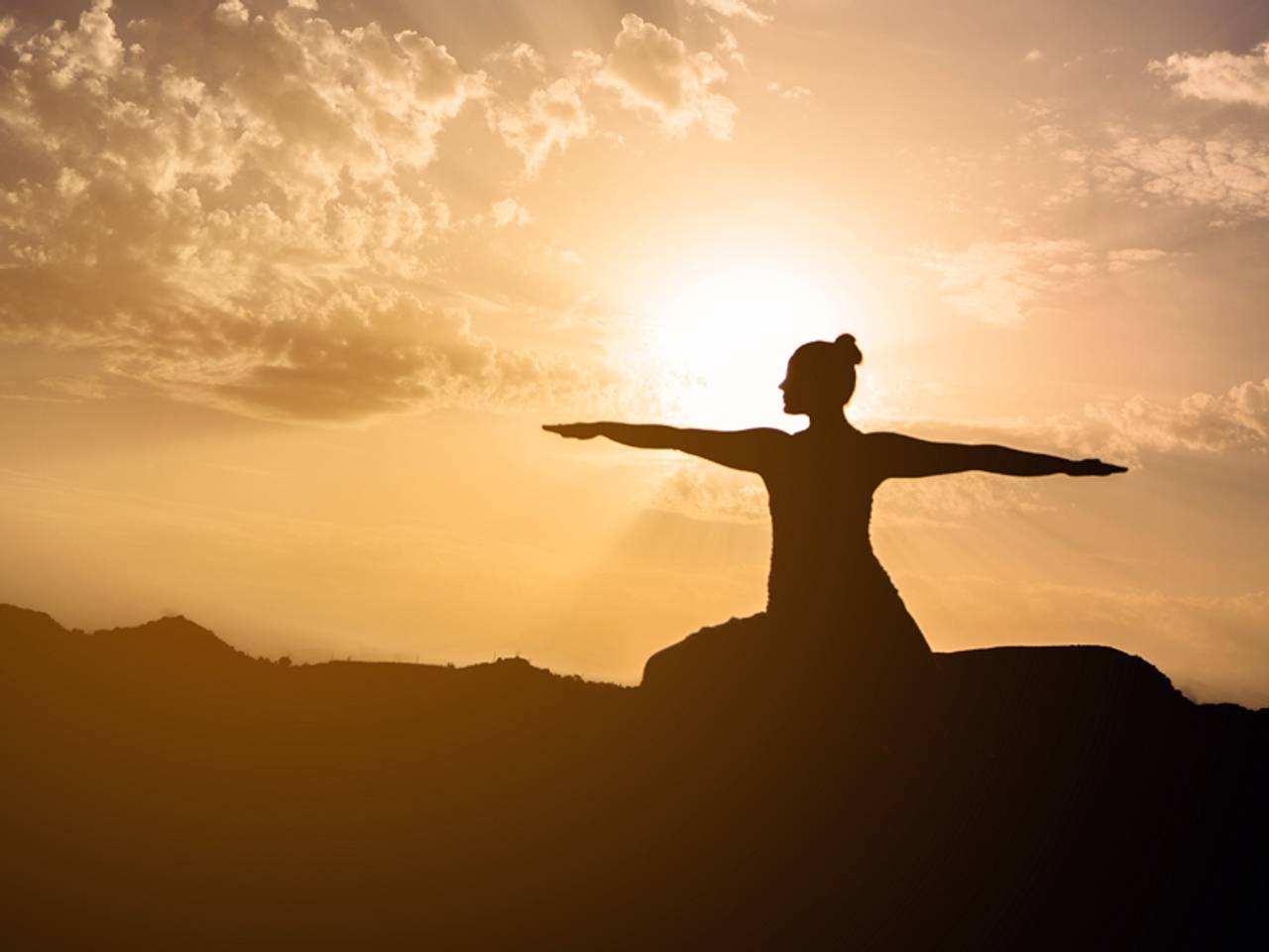 mulher fazendo pose de yoga no nascer do sol