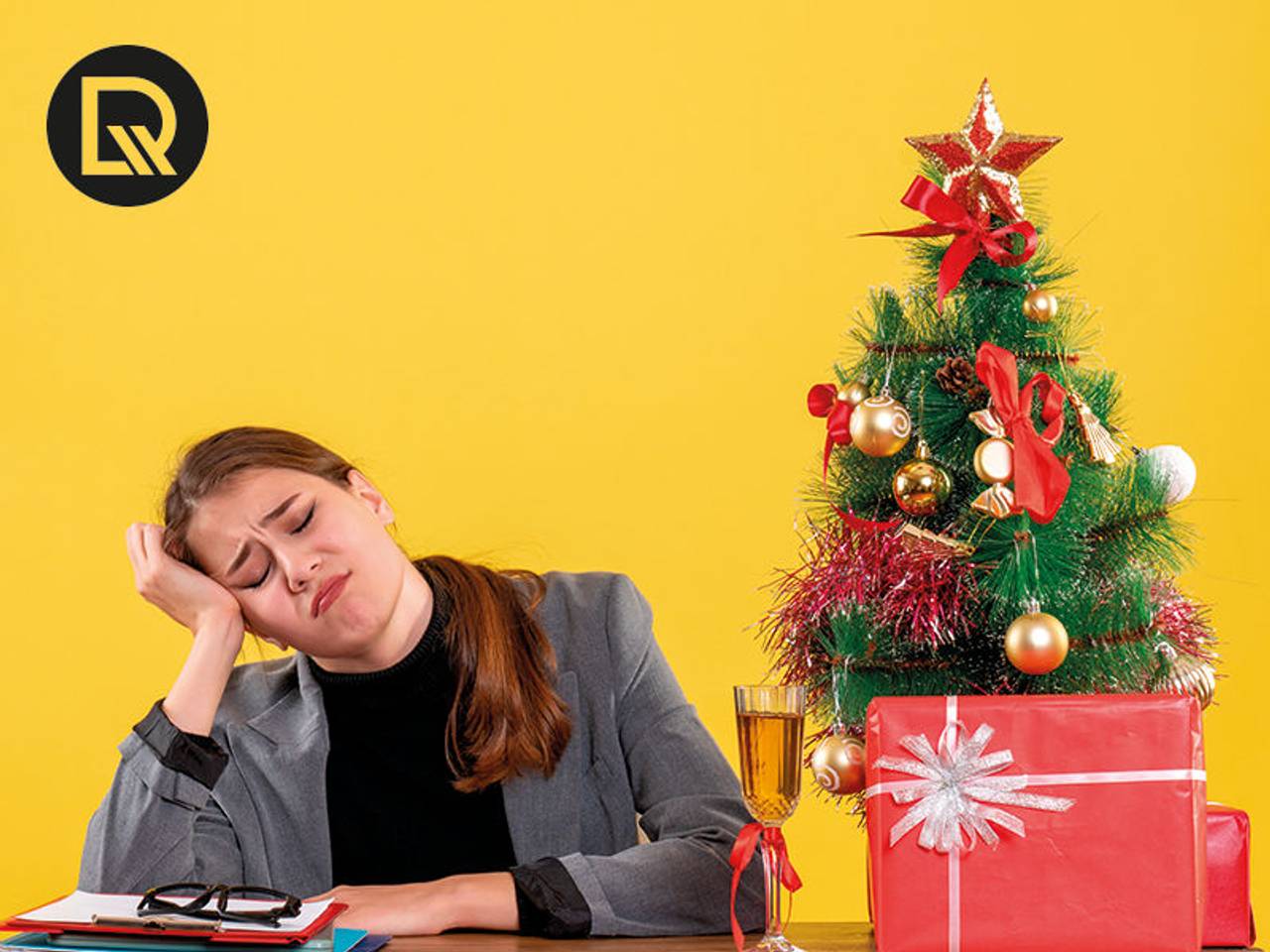 modelo em mesa de escritório, com árvore de natal, trabalhando aborrecida