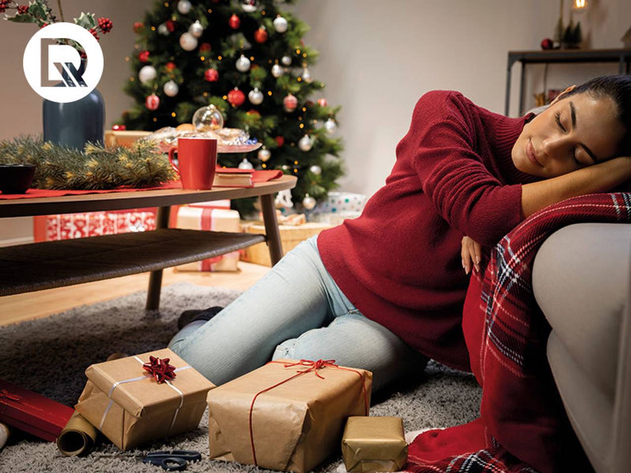 mulher dormindo ao lado de árvore de natal