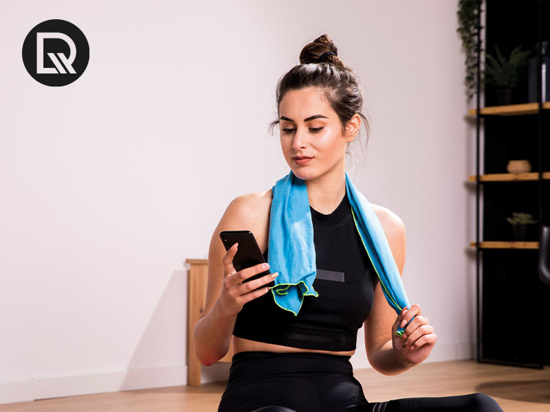 mulher olhando o celular sentada apos praticar exercicio