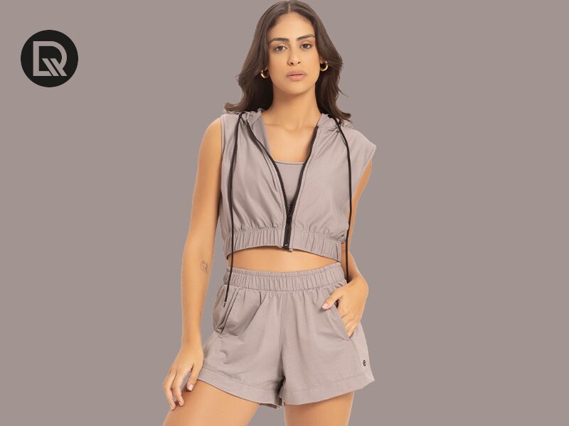 Mulher com roupa esportiva cinza em fundo neutro