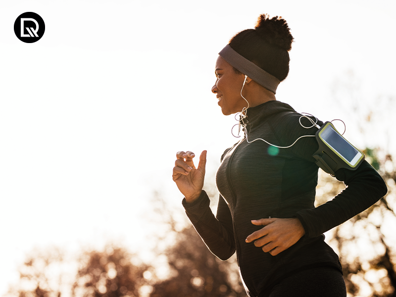Mulher correndo com fones de ouvido e celular.