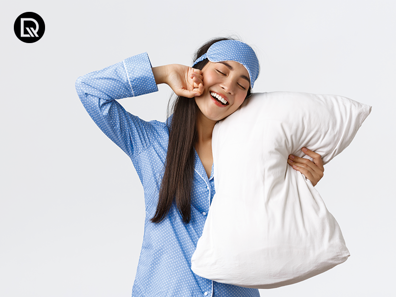 Mulher sorrindo com travesseiro em roupa de dormir